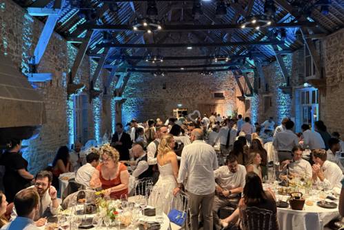 Réception de mariage dans une salle en pierre avec invités et éclairage bleu