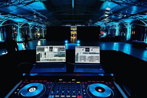 Contrôleur DJ et ordinateurs de régie sous un éclairage bleu